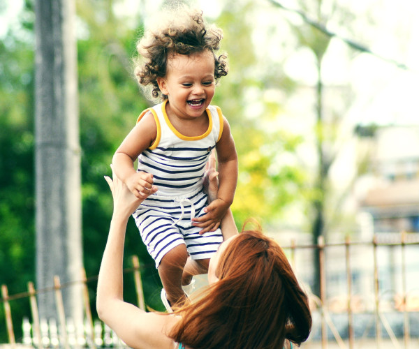 Photo of woman lifting happy child during daytime