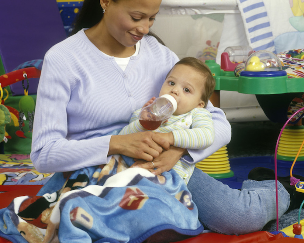 Woman and baby sitting on floor mat